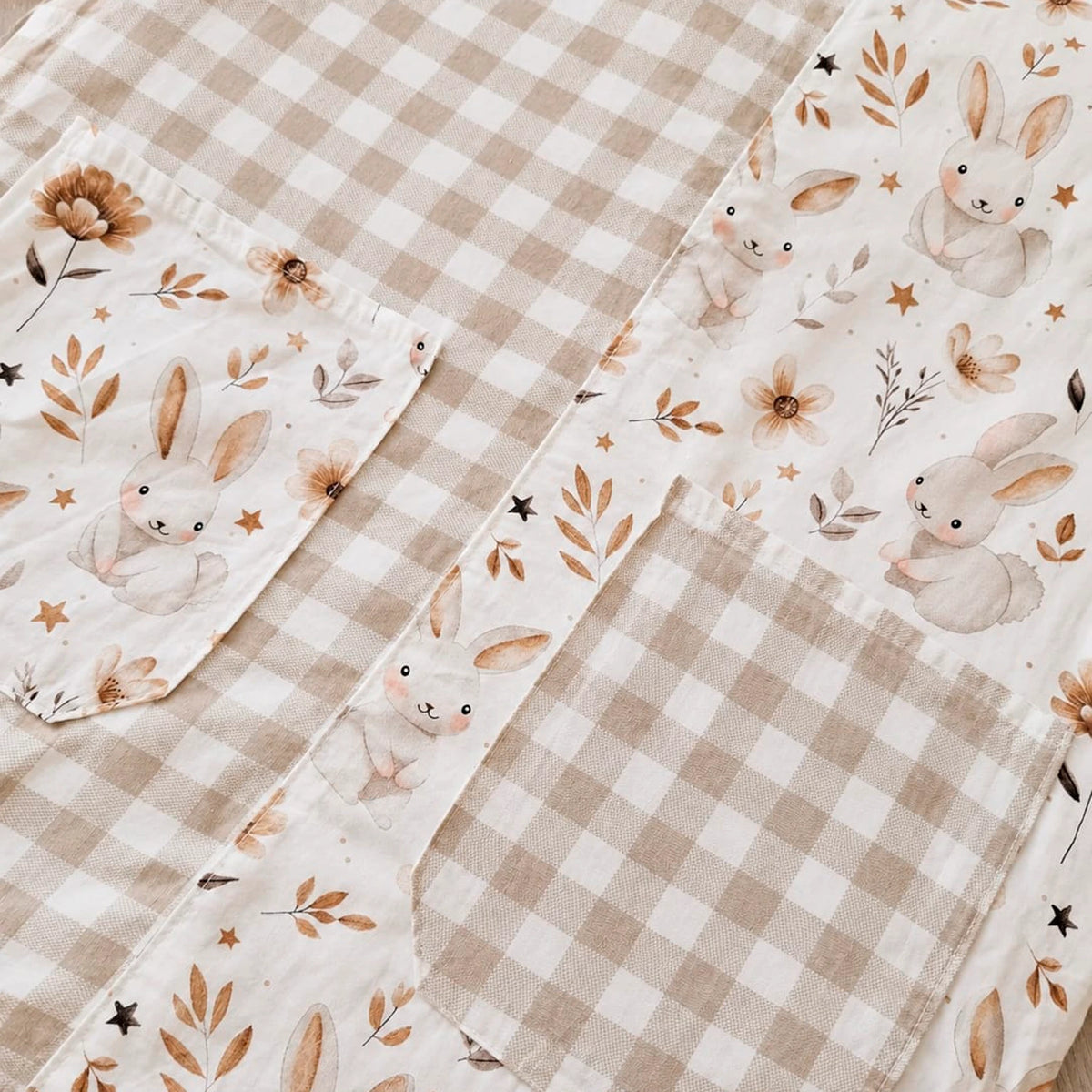 Detalle de tejidos de cuadros beige y estampado de conejitos, flores y estrellas en una estola.