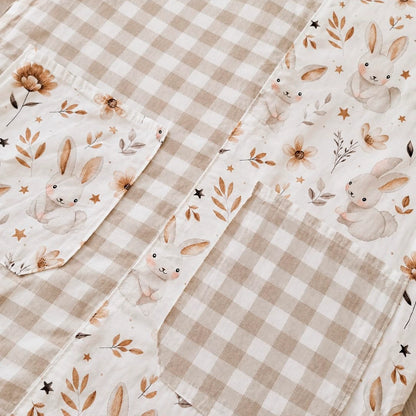 Detalle de tejidos de cuadros beige y estampado de conejitos, flores y estrellas en una estola.
