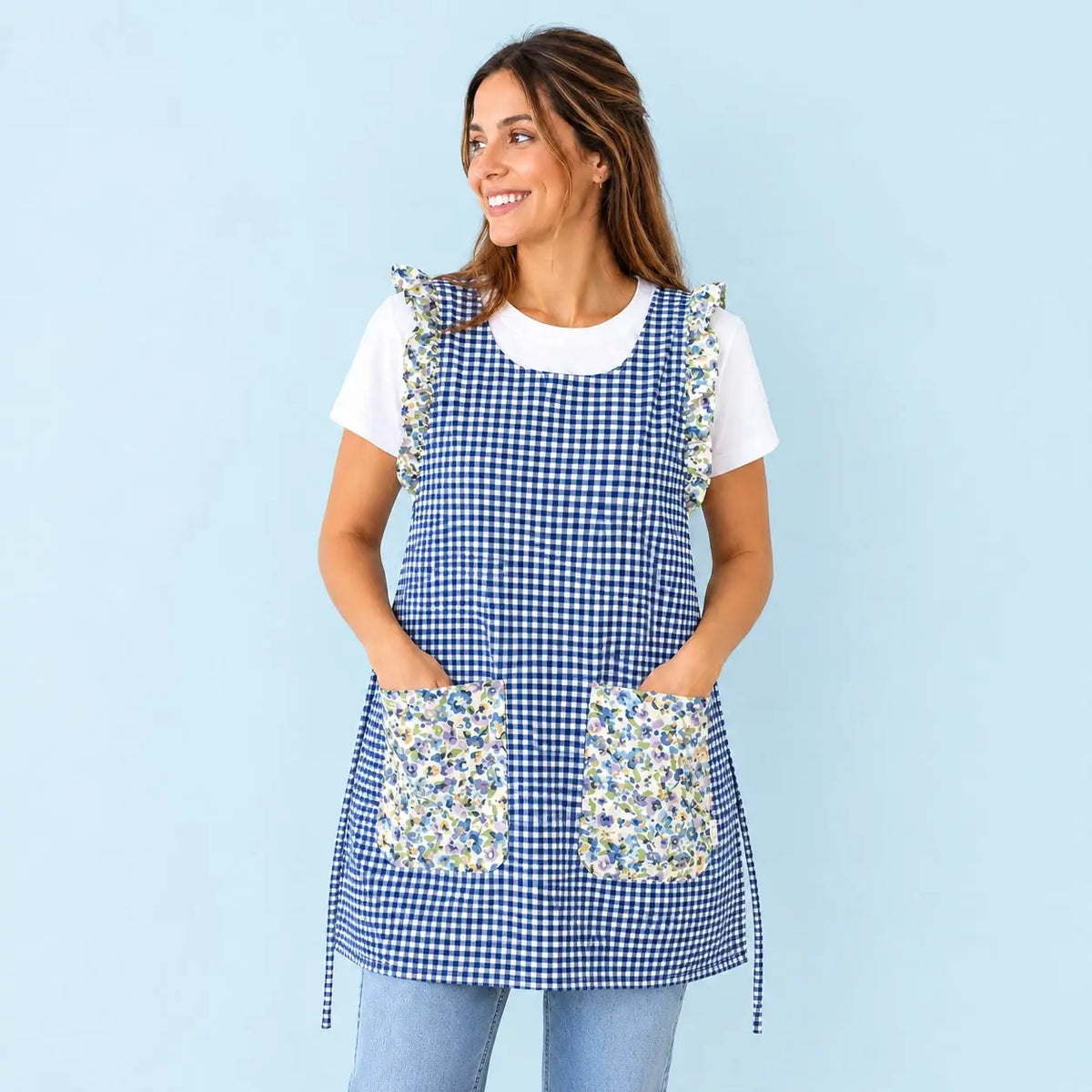 Modelo con estola de cuadros azul marino, volantes y dos bolsillos con flores azules y verdes.